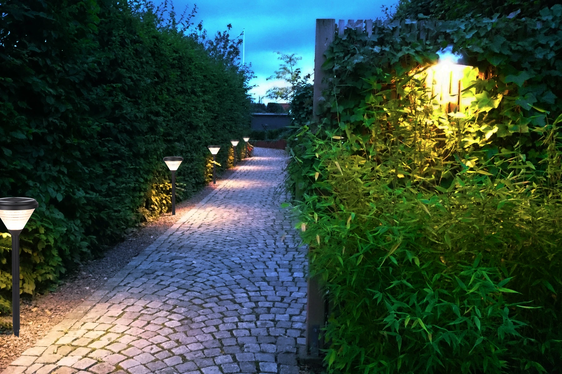 SLL-3004 hourglass bollards along cobblestone path with warm night ambiance