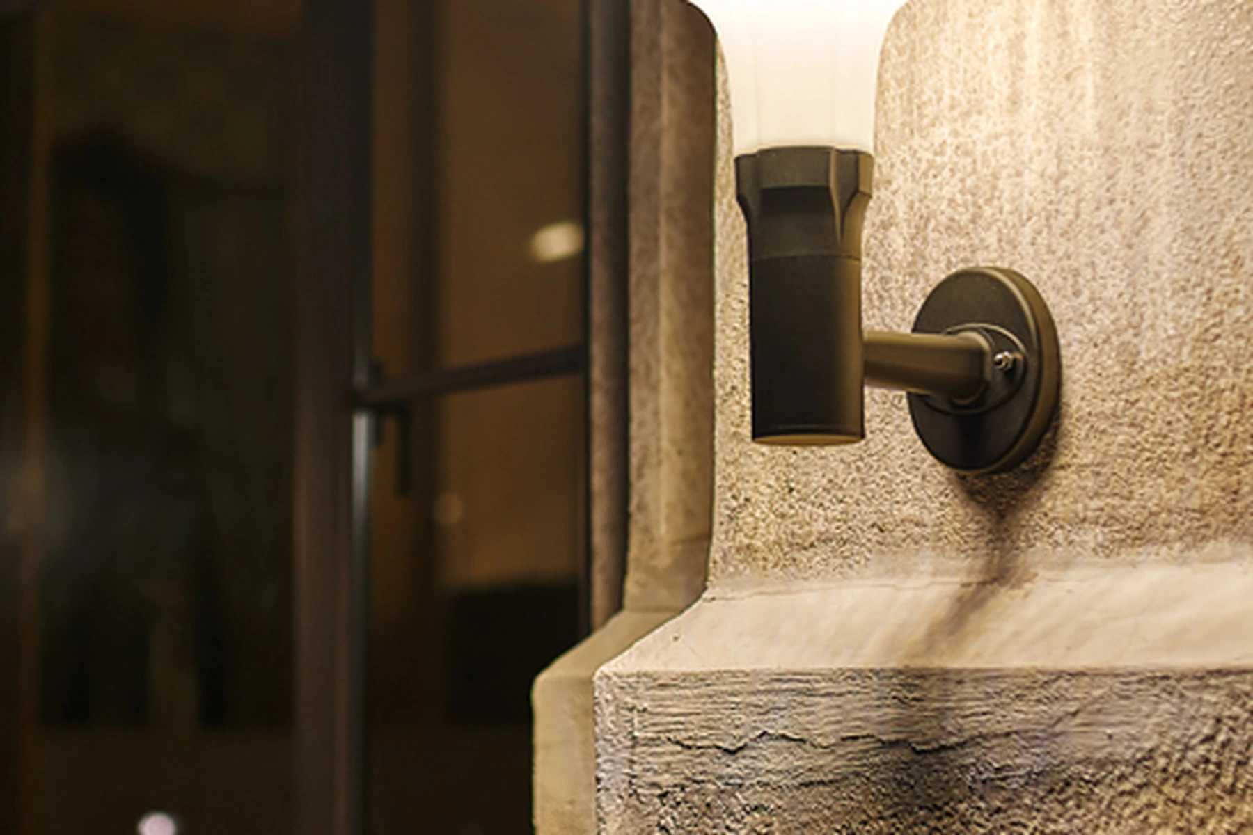 SWL-1004 foreground solar wall sconce highlighting textured stucco masonry