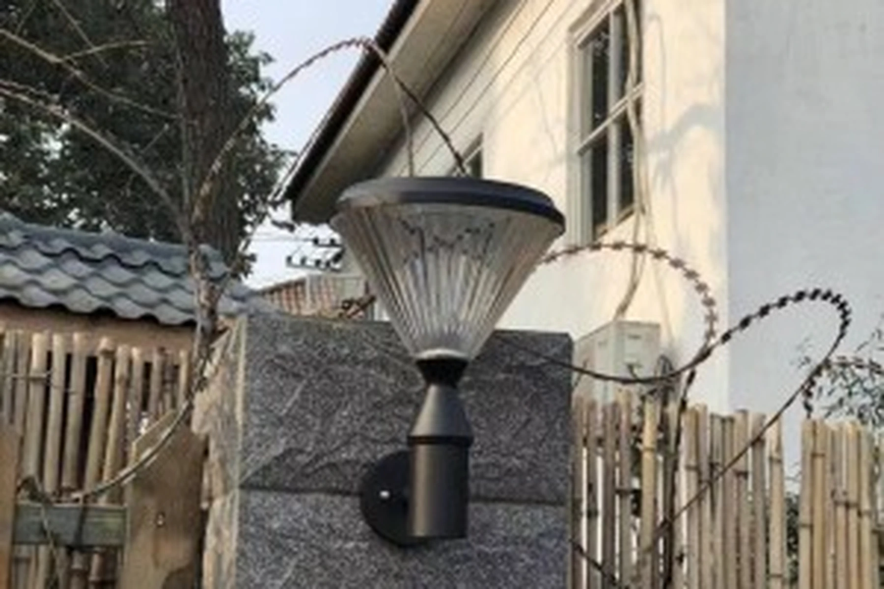 SWL-4005 solar wall sconce mounted on granite perimeter pillar with bamboo fence