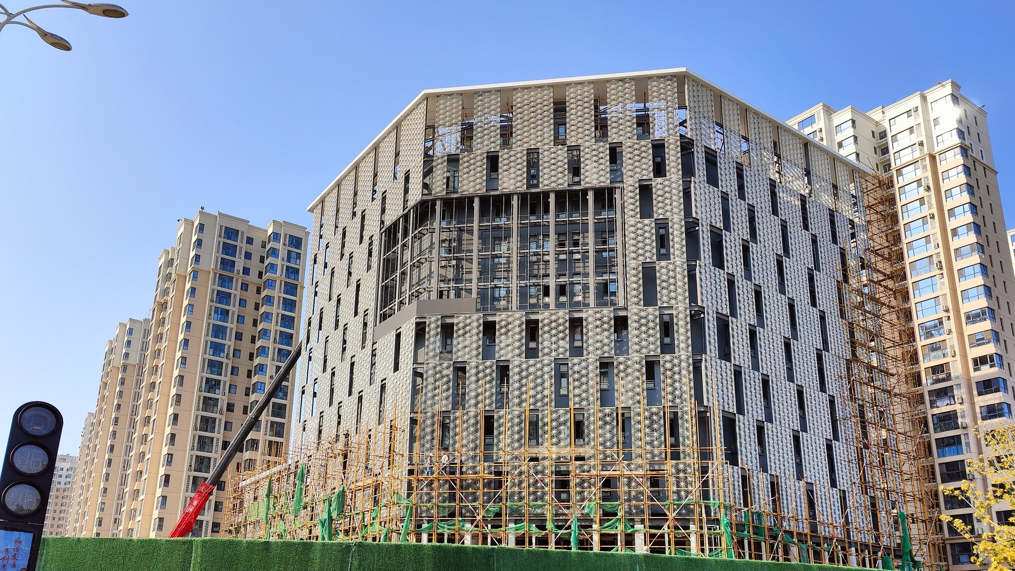 Haitang Building construction phase — fixtures mounted at curtain wall nodes, daytime view